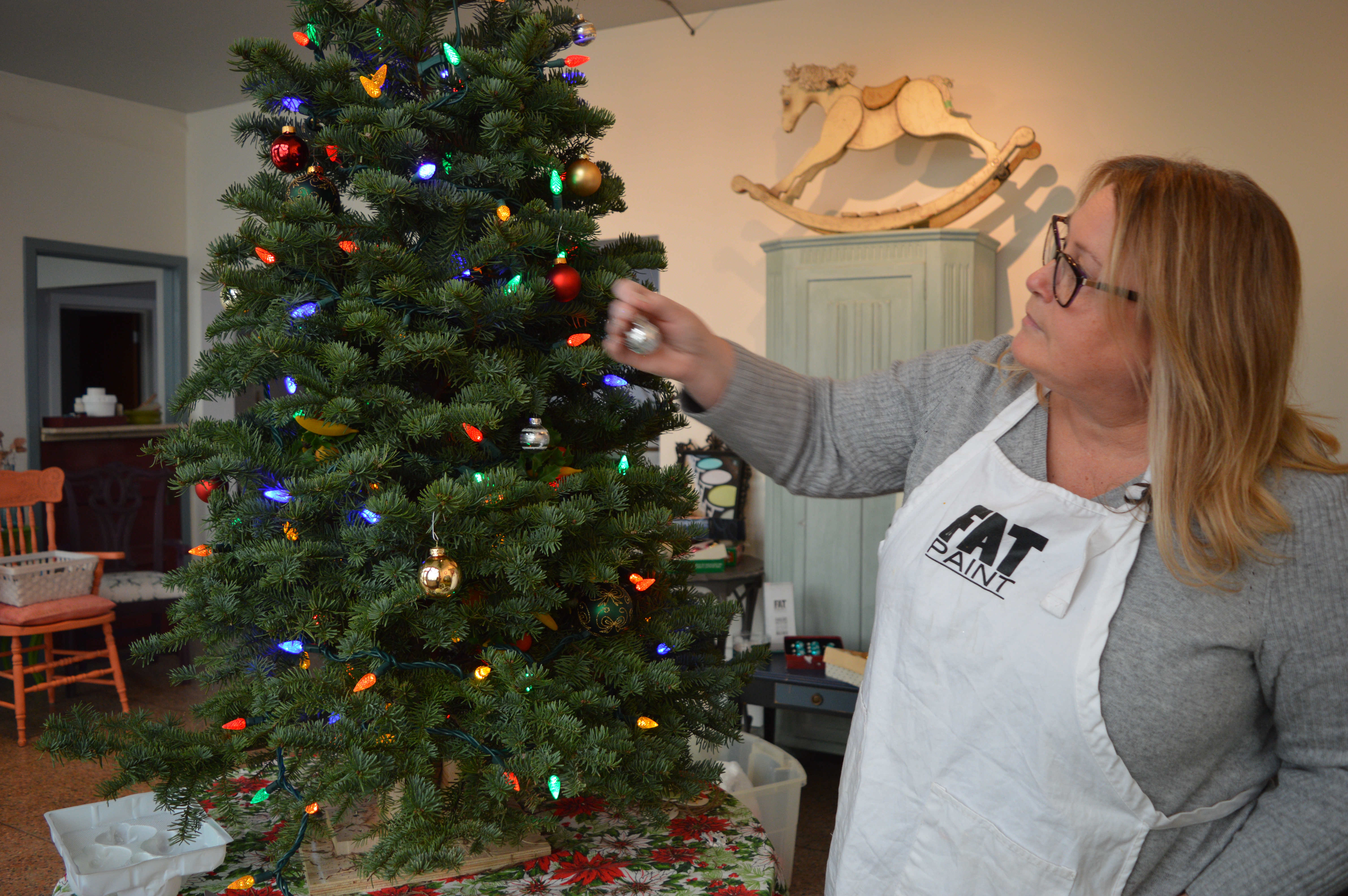 Victoria Lambert, co-owner of The FAT Paint Company, decorates a holiday tree in her shop.